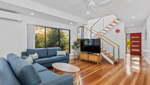Una sala de estar moderna con un sofá azul, un televisor y una escalera de madera.