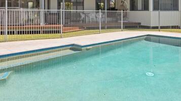 A rectangular swimming pool with a metal fence and steps leading into it.