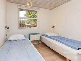 A room with two single beds, a window with a view, a small desk, and a ceiling light fixture.