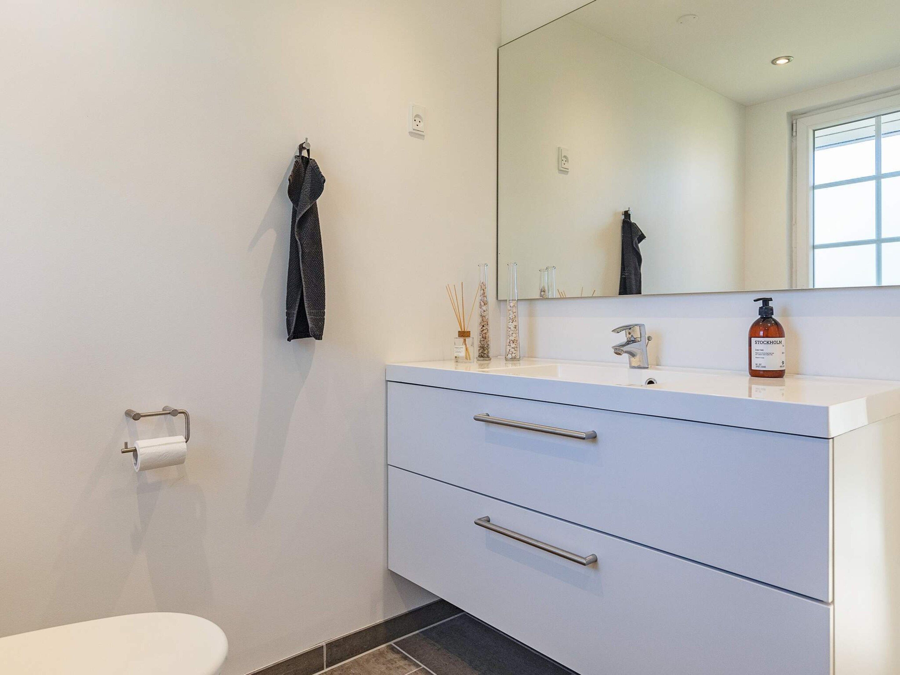 Ein modernes Badezimmer mit Waschbecken, Spiegel und zwei Schubladen.