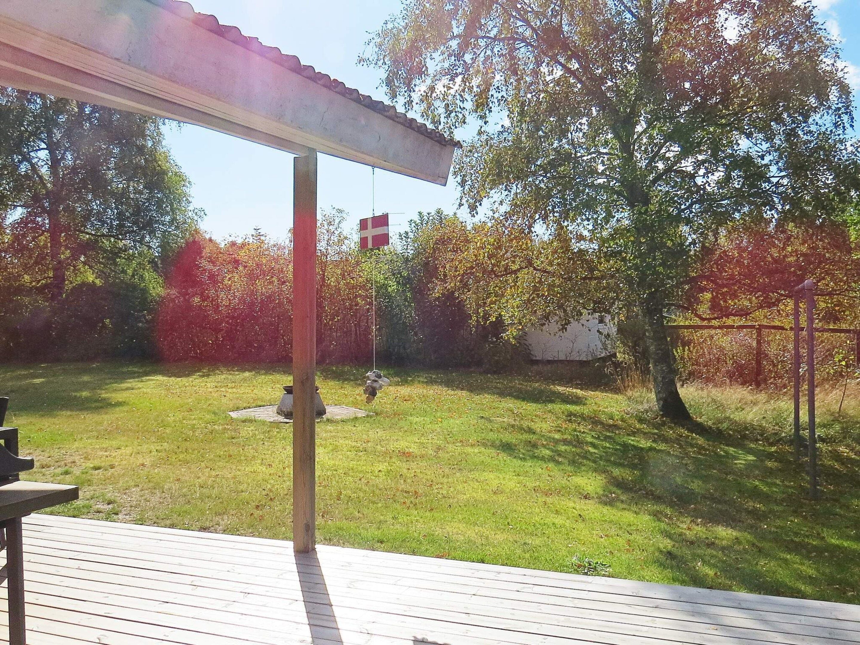 A backyard with a wooden deck, a flag, and trees.