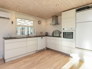 Eine moderne Küche mit weißen Schränken, einem eingebauten Backofen und einer Edelstahl-Dunstabzugshaube.