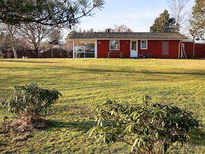 A red building with a number '10' on the side, a glass door, and a small patio area. - 4 Person Holiday Home in Hals (Hals)