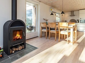 A modern kitchen with a wood-burning stove, wooden dining table, chairs, and pendant lights. - 4 Person Holiday Home in Hals (Hals)