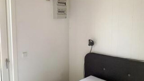 A room with a bed, a white door, and a wall-mounted electrical outlet. - 4 Person Holiday Home in Hals (Hals)