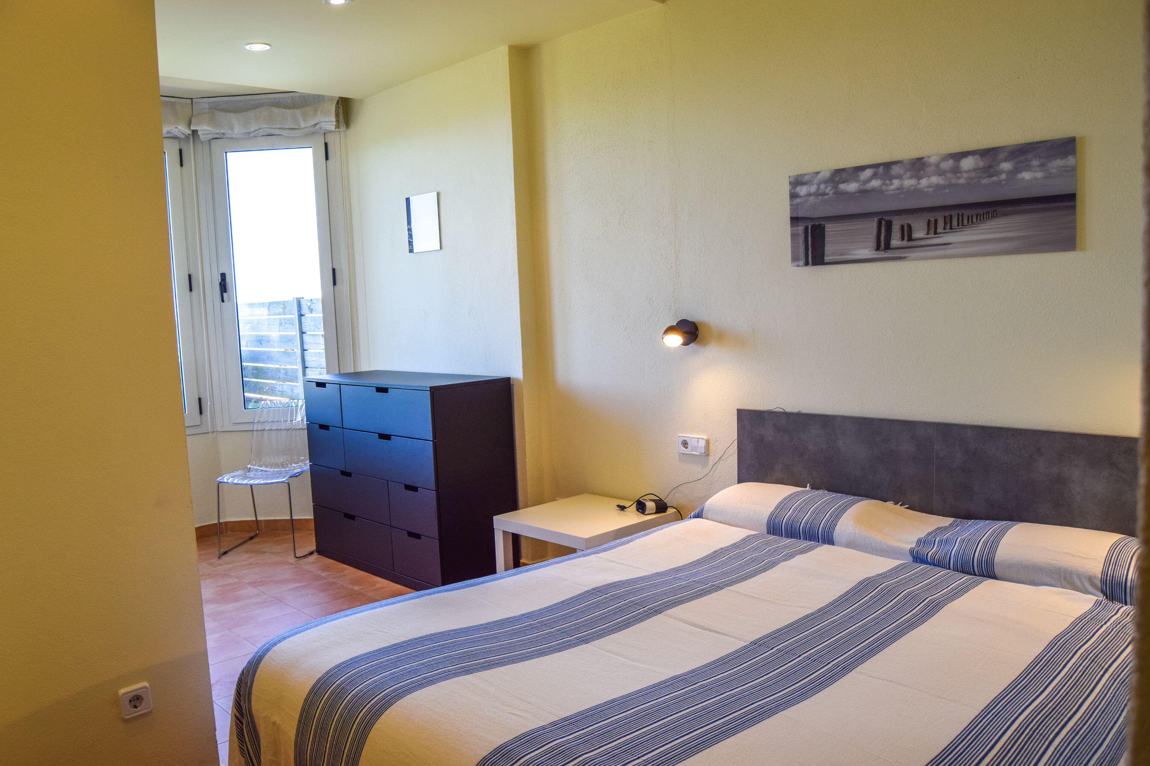 A bedroom with a bed, a desk, a chair, and a dresser.