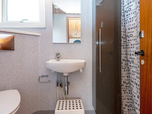 A bathroom with a white sink, a mirror, a shower curtain with water-related words, and a toilet. - 6 Person Holiday Home in Juelsminde-by Traum (Juelsminde)