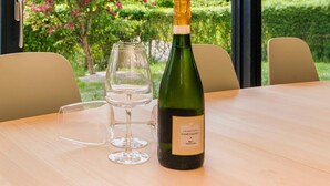 A bottle of champagne and two wine glasses on a table with a view of a garden. - 6 Person Holiday Home in Juelsminde-by Traum (Juelsminde)