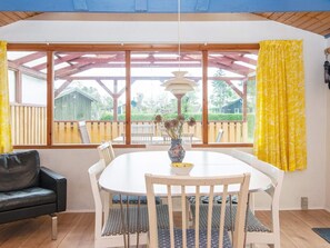 A dining area with a round table, chairs, and a vase with flowers. - 6 Person Holiday Home in Juelsminde-by Traum (Juelsminde)