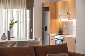 A modern kitchen with wooden cabinets, a built-in oven, and a refrigerator. - Actea Seaview Villas - Holiways Collection (Kissamos)