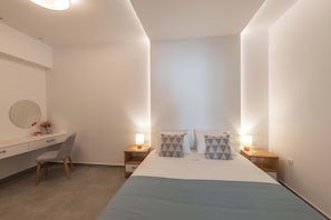 A modern hotel room with a bed, bedside tables, a desk, and a chair. - Actea Seaview Villas - Holiways Collection (Kissamos)