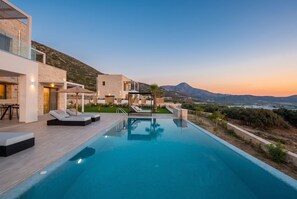 A modern pool area with lounge chairs, a clear view of the sea, and a mountainous backdrop. - Actea Seaview Villas - Holiways Collection (Kissamos)