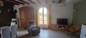 A living room with a TV, a sofa, a chair, and a wooden cabinet.