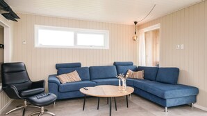 A living room with a blue sofa, a black chair, and a round wooden table. - 5 Star Holiday Home in Haderslev (Haderslev)