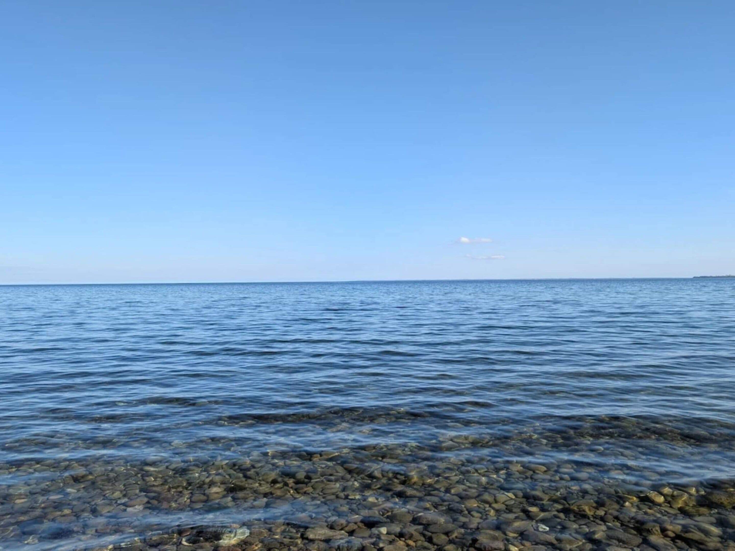 A clear view of a calm sea with a rocky shoreline.