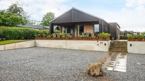 A modern house with a covered patio, a gravel driveway, and a number 63 sign. - 5 Star Holiday Home in Haderslev (Haderslev)