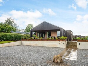 A modern house with a covered patio, a gravel driveway, and a number 63 sign. - 5 Star Holiday Home in Haderslev (Haderslev)