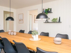 Un comedor con una larga mesa de madera, sillas negras e iluminación colgante.