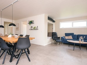 Un espace de vie moderne comprenant un coin repas, un canapé et une petite table agrémentée d’objets décoratifs.