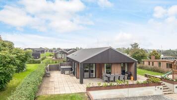 A modern residential complex with a patio area, outdoor seating, and a play area.