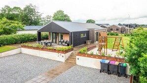 A modern outdoor area with a covered seating area, a play structure, and a gravel pathway leading to a building. - 5 Star Holiday Home in Haderslev (Haderslev)