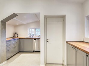 A modern kitchen with a wooden countertop, stainless steel appliances, and a window with a view.