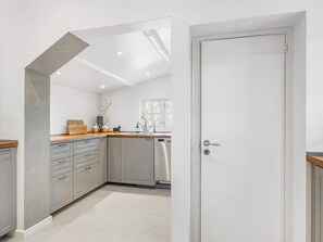 A modern kitchen with grey cabinets, a wooden countertop, and a dishwasher.