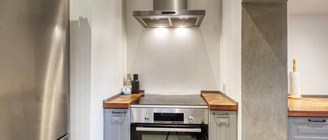 A kitchen with a stainless steel refrigerator, a Bosch oven, and a wooden countertop.