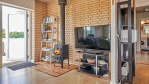 A modern living room with a brick wall, a fireplace, a TV, and a bookshelf. - 12 Person Holiday Home in Aakirkeby (Akirkeby)