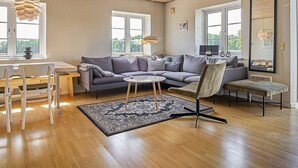 A modern living room with a wooden ceiling, grey sofas, a round coffee table, and a large mirror. - 12 Person Holiday Home in Aakirkeby (Akirkeby)