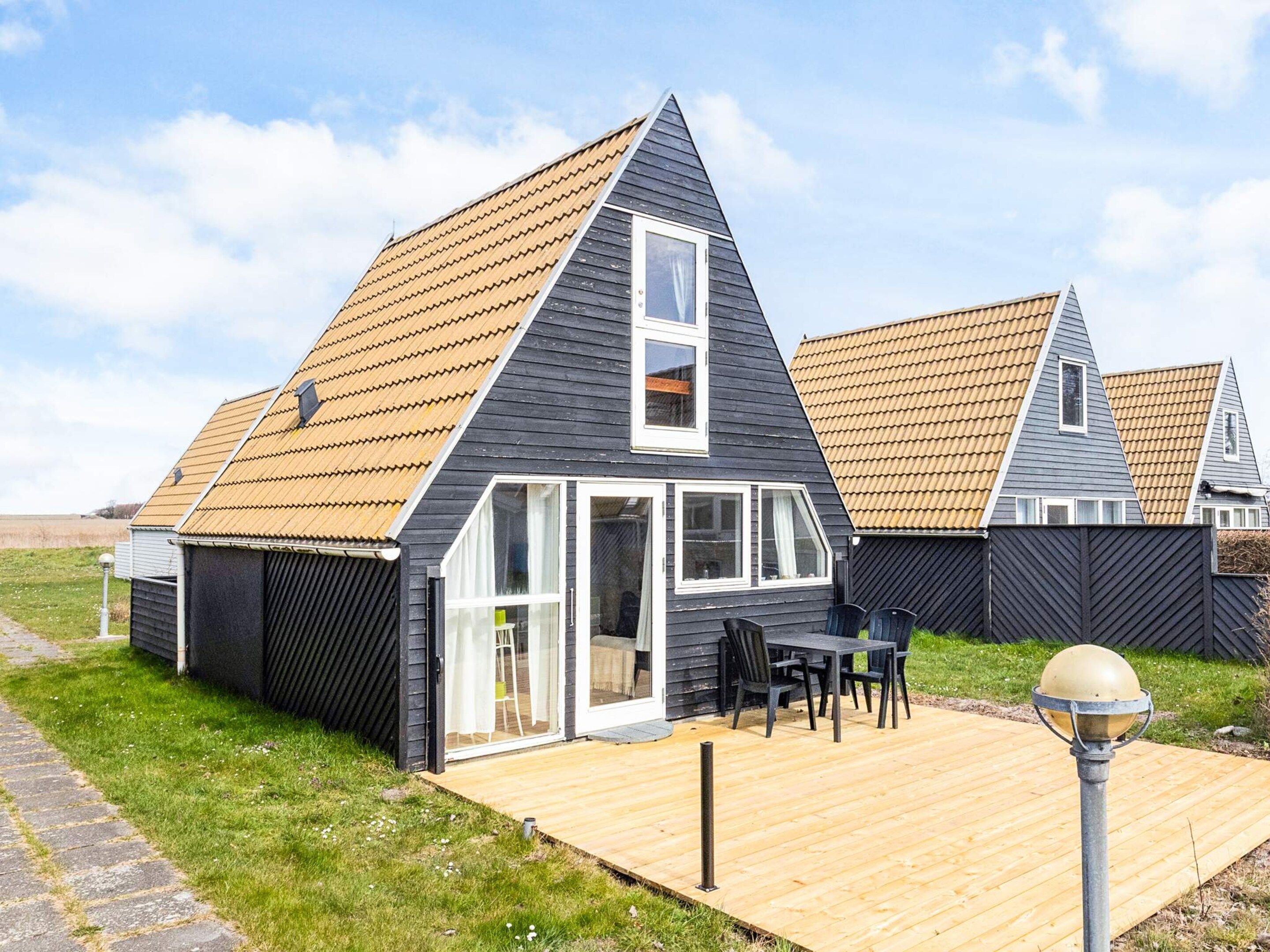 A modern house with a sloped roof, a wooden deck, and a garage.