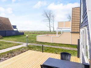 Una terraza moderna al aire libre con piso de madera y una mesa y una silla.