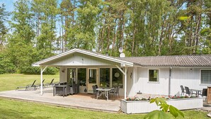 Un chalet de plain-pied doté d’un patio couvert, d’un espace salon extérieur et d’un petit jardin.