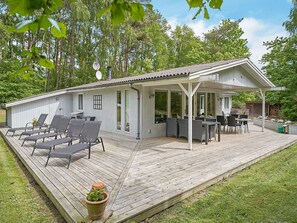 A covered outdoor deck with seating and a dining area, surrounded by trees. - 6 Person Holiday Home in Nexo (Nexø)