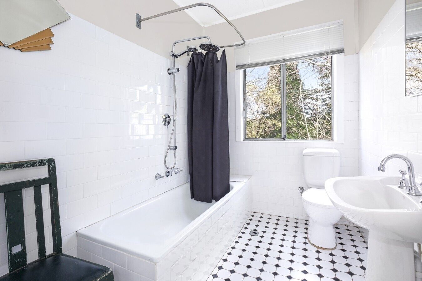 A bathroom with a bathtub, toilet, and sink, featuring white tiles and a black and white patterned floor.