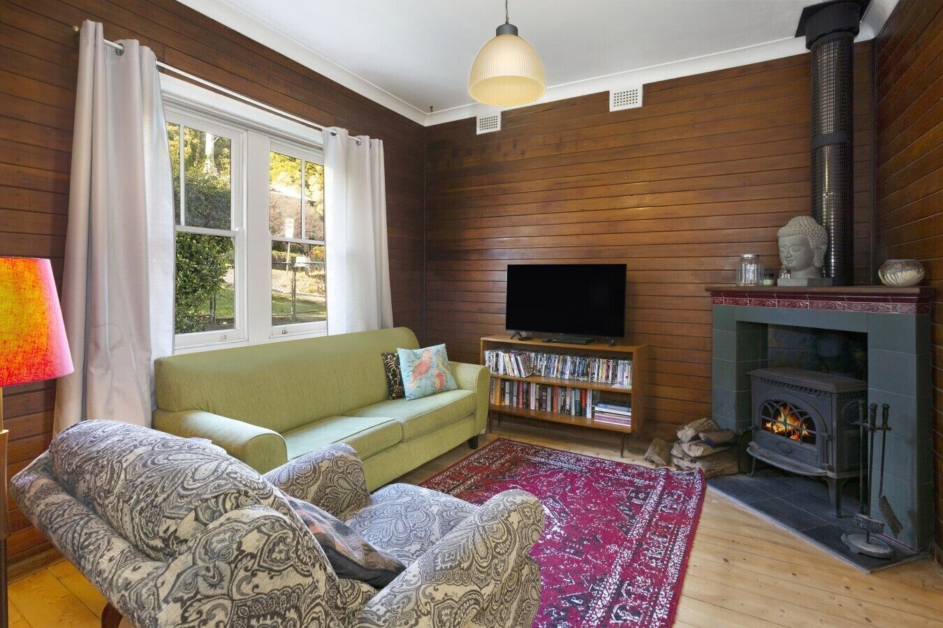 A cozy living room with a sofa, a television, a bookshelf, and a fireplace.