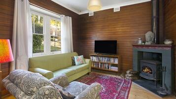 A cozy living room with a sofa, a television, a bookshelf, and a fireplace.