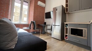A compact kitchen with a refrigerator, microwave, and a flat-screen TV mounted on the wall. - Tony's Apartments (Rijeka)