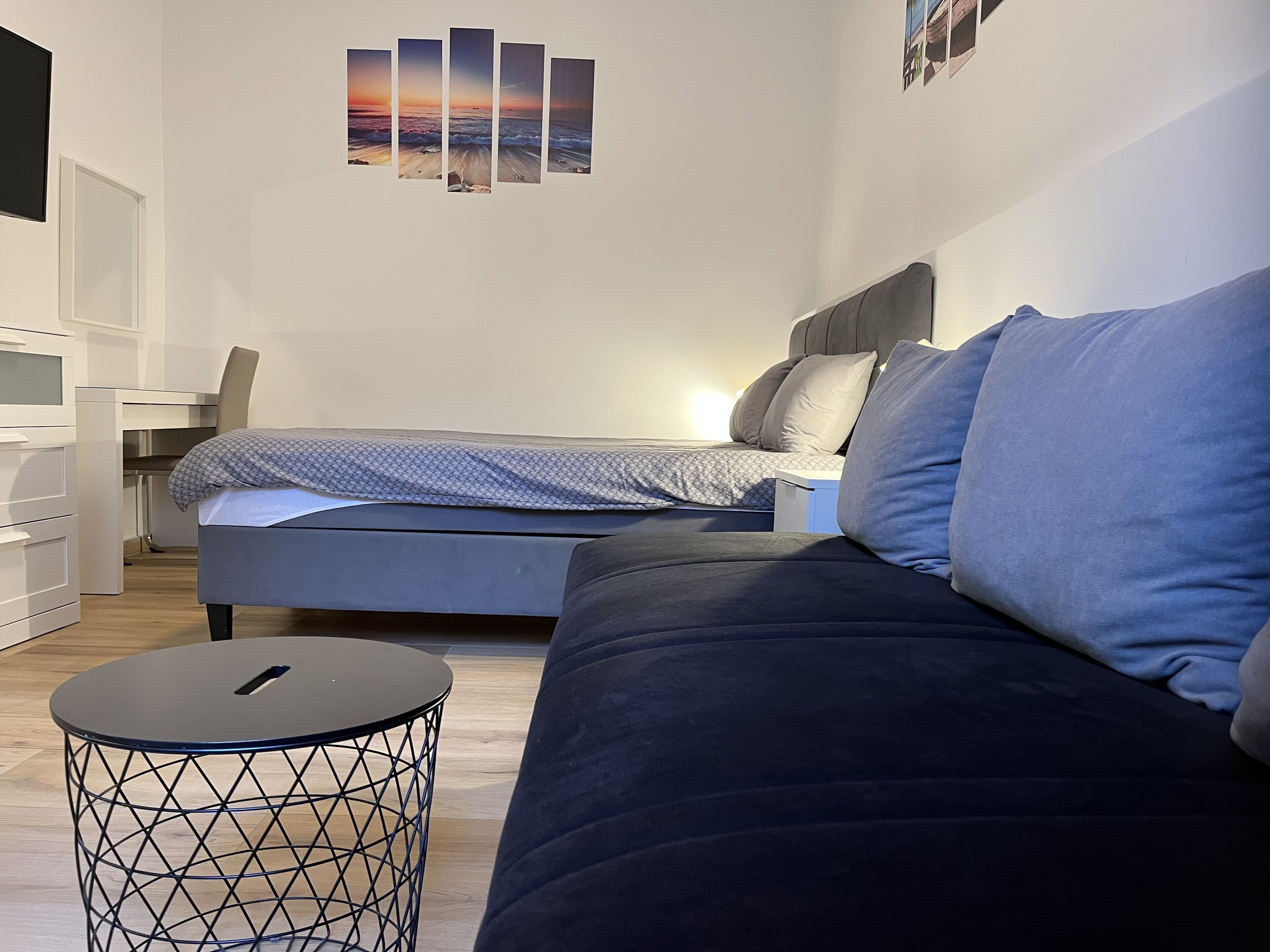Un dormitorio moderno con cama, sofá, escritorio y una mesa redonda.