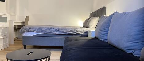 Un dormitorio moderno con cama, sofá, escritorio y una mesa redonda.