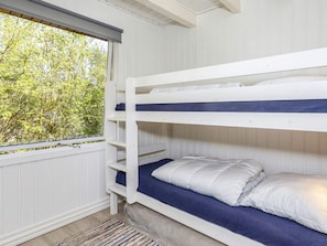 A bunk bed room with a window overlooking greenery.