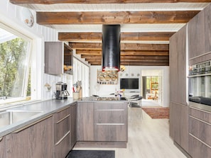 A modern kitchen with wooden cabinets, a central island, and a black range hood.