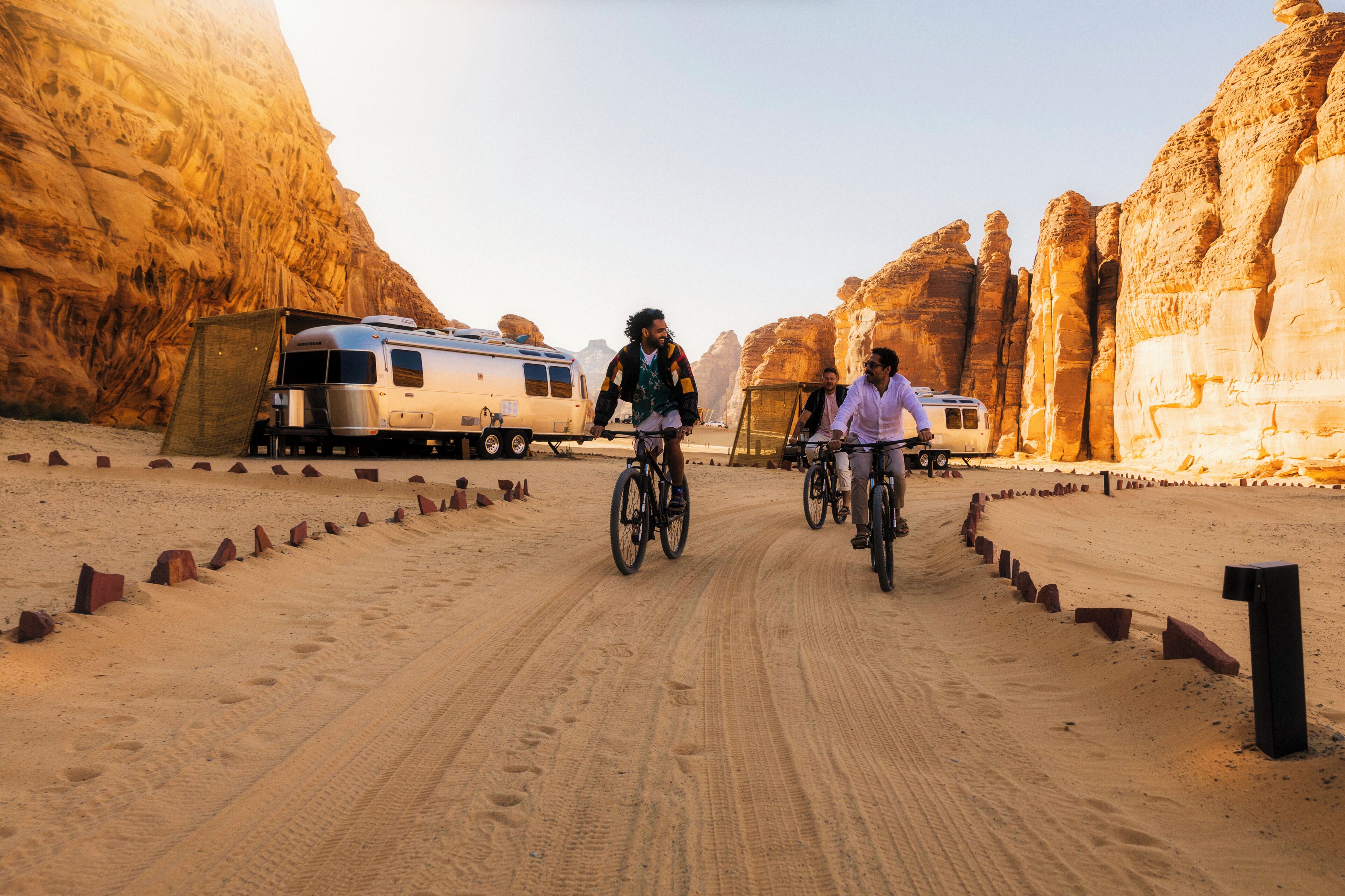 A desert road with a caravan and two cyclists.