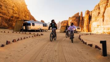 A desert road with a caravan and two cyclists.