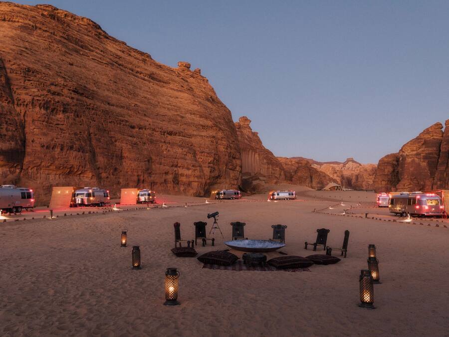 Campa de desierto con vehículos recreativos, faroles y un telescopio.