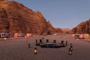 A desert campsite with RVs, lanterns, and a telescope.