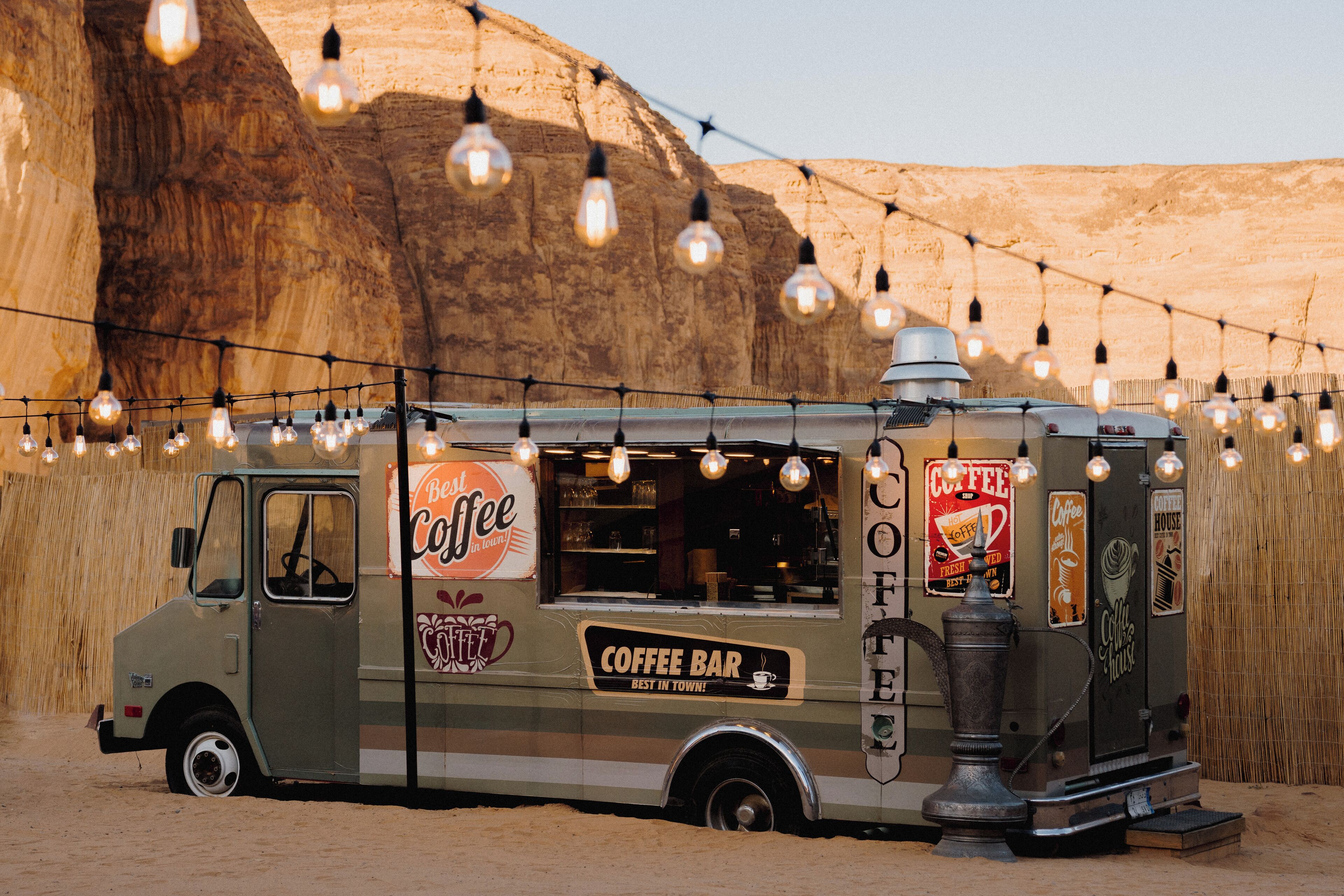 Un camion-restaurant de style rétro, équipé d’un bar à café et arborant les inscriptions « Le meilleur de la ville ! » et « Bar à café ».