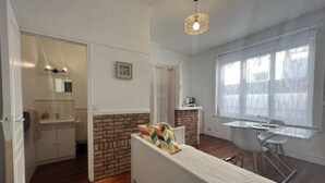 Une cuisine moderne avec un mur d’accent en briques, un comptoir blanc et un luminaire suspendu.