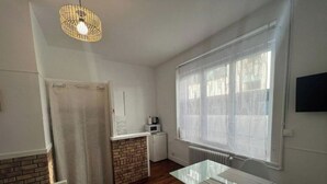 Une pièce de taille modeste comprenant un coin cuisine, une table à manger et une grande fenêtre.