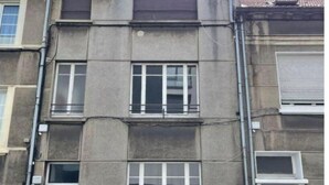 Un immeuble à plusieurs étages doté d’une façade sobre, de grandes fenêtres et d’un petit hall d’entrée avec une porte.
